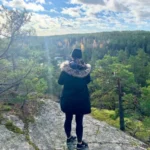Woman enjoying a scenic viewpoint overlooking endless pine forest. A peaceful moment during a guided hike near Stockholm.