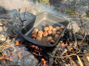 Traditionelle schwedische Fleischbällchen brutzeln über einem offenen Feuer - Mittagspause auf unserer Naturwanderung in der Nähe von Stockholm.