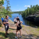 Small group enjoying a sunny stop by a peaceful lake in Nacka Nature Reserve.