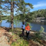 Hikers exploring rocky lakeside terrain under pine trees in the heart of Nacka Nature Reserve, just outside Stockholm.