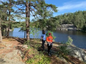 Wanderer erkunden das felsige Gelände am Seeufer unter Kiefern im Herzen des Nacka-Naturreservats vor den Toren Stockholms.