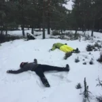 Kunden machen Schneeengel während einer geführten Winterwanderung in der Nähe von Stockholm