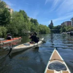 Kayakistas remando por un tranquilo canal hacia la ciudad
