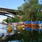 Deslícese por un apacible canal entre clásicos barcos suecos y bajo un puente de la ciudad durante nuestra excursión en kayak por Estocolmo.