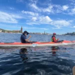 Dos kayakistas en mar abierto con los monumentos emblemáticos de Estocolmo a lo lejos.