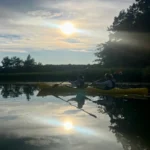 Dubbelkajak som fångar de sista strålarna av kvällsljuset med perfekta reflektioner på vattnet.
