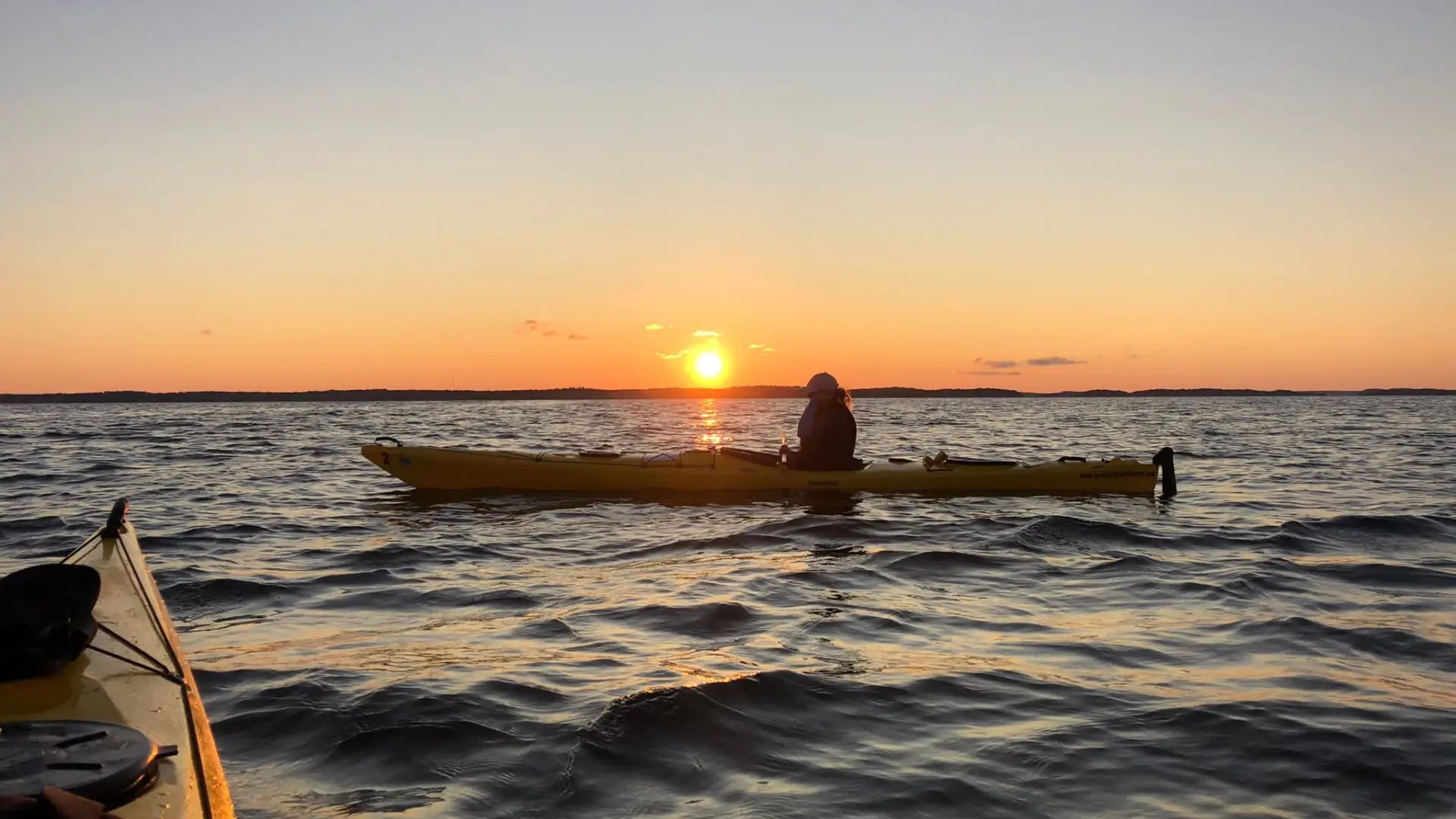 Imagen de un kayakista junto al sol poniente, mientras participa en una excursión guiada por el archipiélago al atardecer