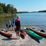 Kajakpaddlare förbereder sin utrustning i strandkanten under en guidad kajaktur i Stockholms skärgård.