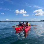 En grupp kajakpaddlare tar en paus och paddlar rafting mitt ute i Stockholms skärgård.