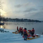 Un grupo prepara los kayaks en la orilla nevada de un río antes de lanzarse a las gélidas aguas para una excursión invernal guiada por Estocolmo.